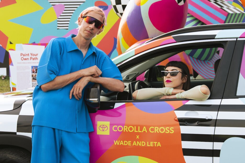Wade and Leta posing in a car in front of their work titled "Paint Your Own Path" for Toyota, Bonnaroo, and Saatchi & Saatchi