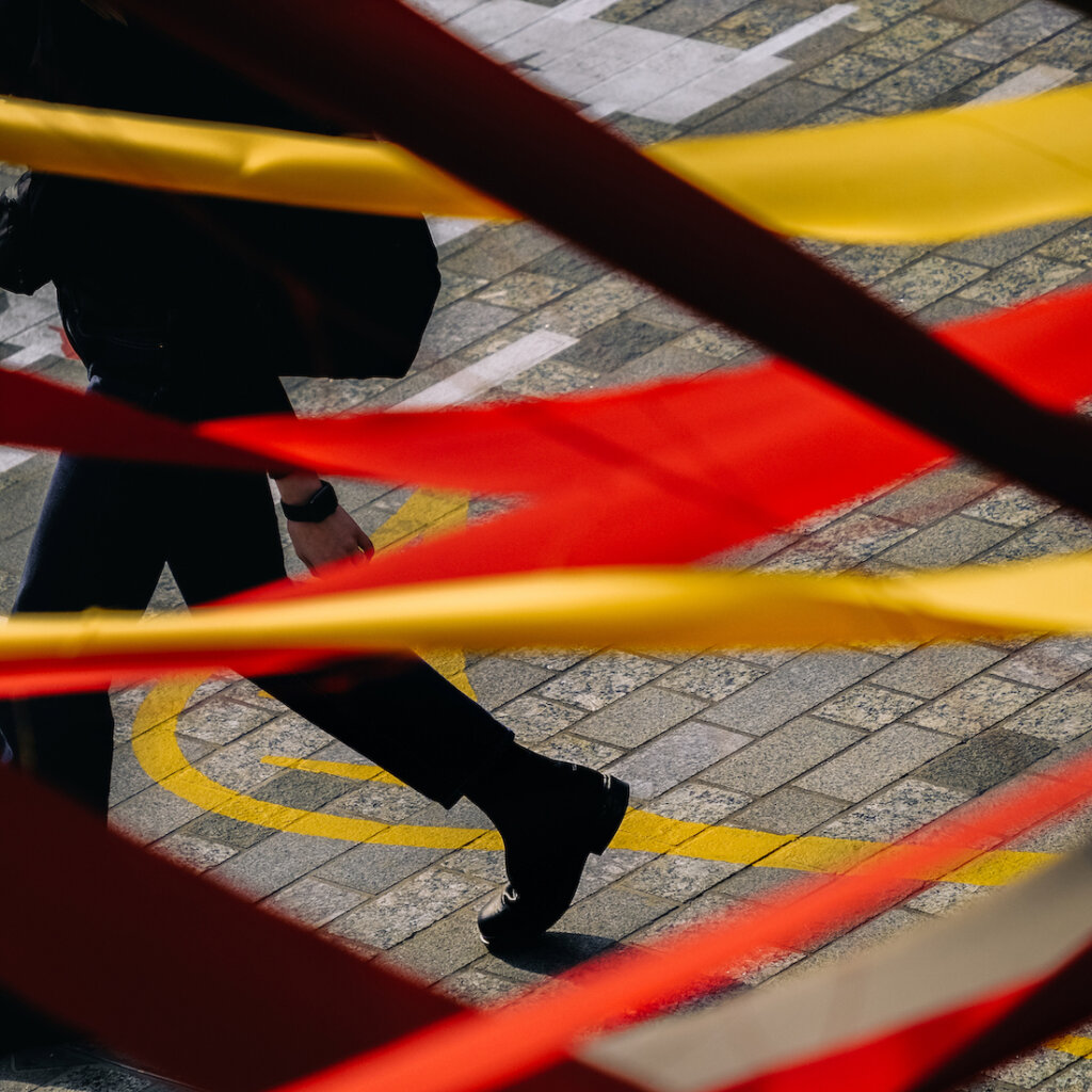 A Person Walks Behind Red And Yellow Ribbons Streamed Back And Forth