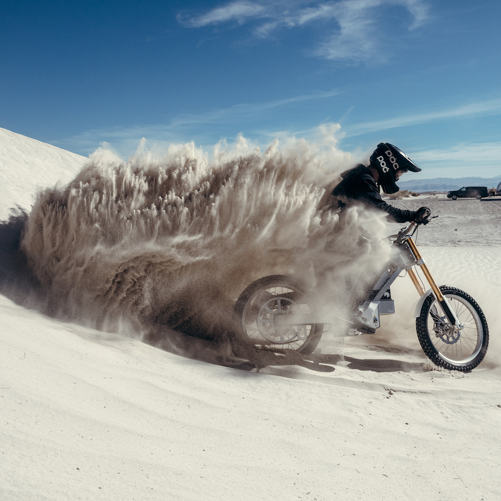 An Off-road Motorcyclist Kicks Up Desert Sand On A Dune