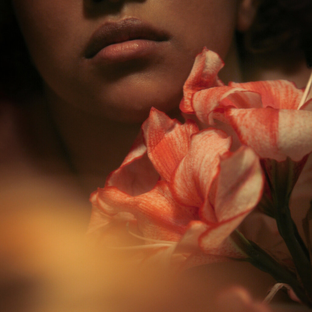 A Woman Holding A Flower Indoors At Night Time